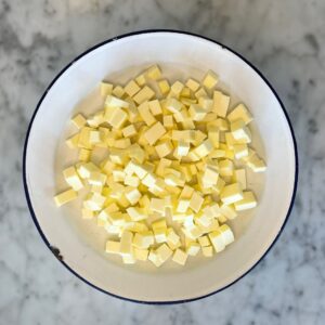 1/4 inch cubed butter on plate sitting on marble countertop.